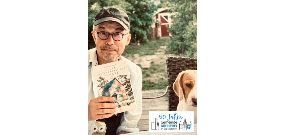 Lesung von Henni Nachtsheim Auf dem Foto ist Henni Nachtsheim zu sehen, er hält sein Buch in der Hand, neben ihm sitzt ein Hund