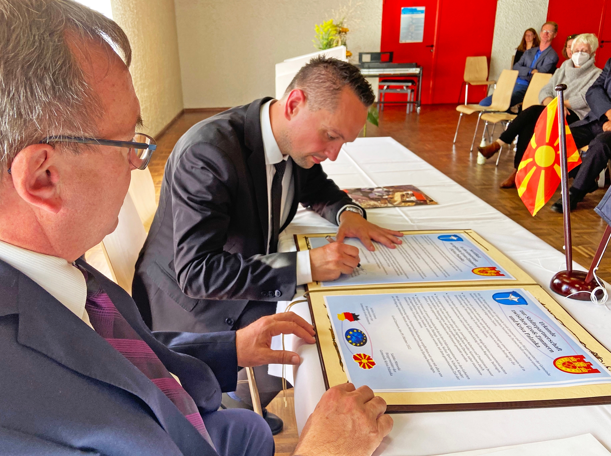 Der Bürgermeister Achim Grimm und Sasko Mitovski unterschreiben die Urkunden