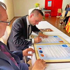 Der Bürgermeister Achim Grimm und Sasko Mitovski unterschreiben die Urkunden
