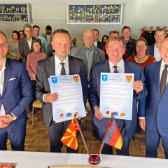 Auf dem Bild sieht man der Bürgermeister Achim Grimm und Städtepartnerschaften mit Urkunden ins Hand