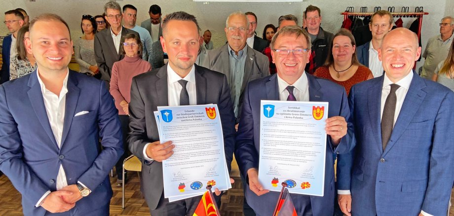 Auf dem Bild sieht man der Bürgermeister Achim Grimm und Städtepartnerschaften mit Urkunden ins Hand