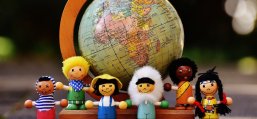 Puppen die verschiedene Nationalitäten verkörpern vor einem kleinen Globus