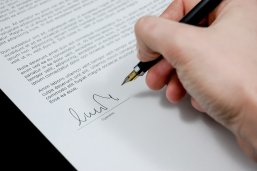 Eine Hand, die mit einem Füller auf einem Blatt Papier untetschreibt