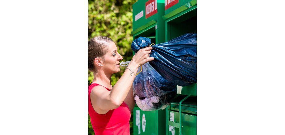 Altkleidercontainer Auf dem Bild sieht man eine Frau an Altkleidcontainer