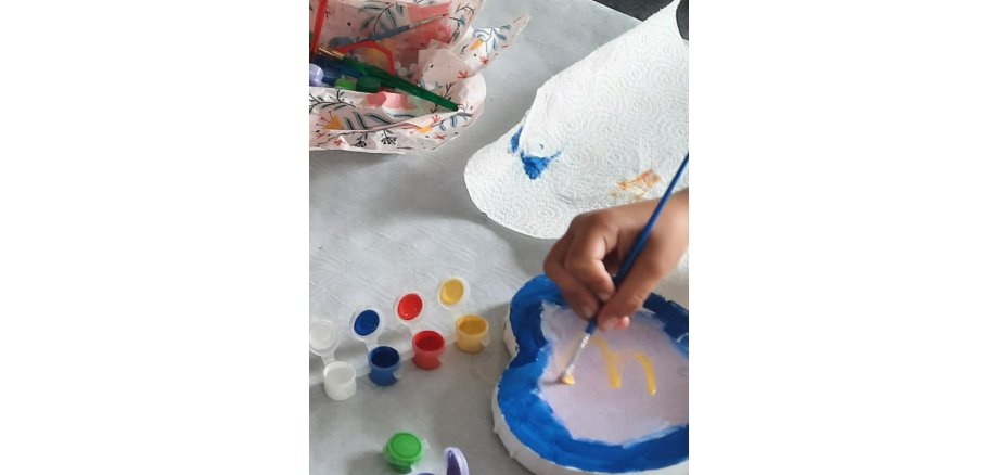 Auf dem Foto sieht man einen Teilnehmer beim Bemalen der Leinwände