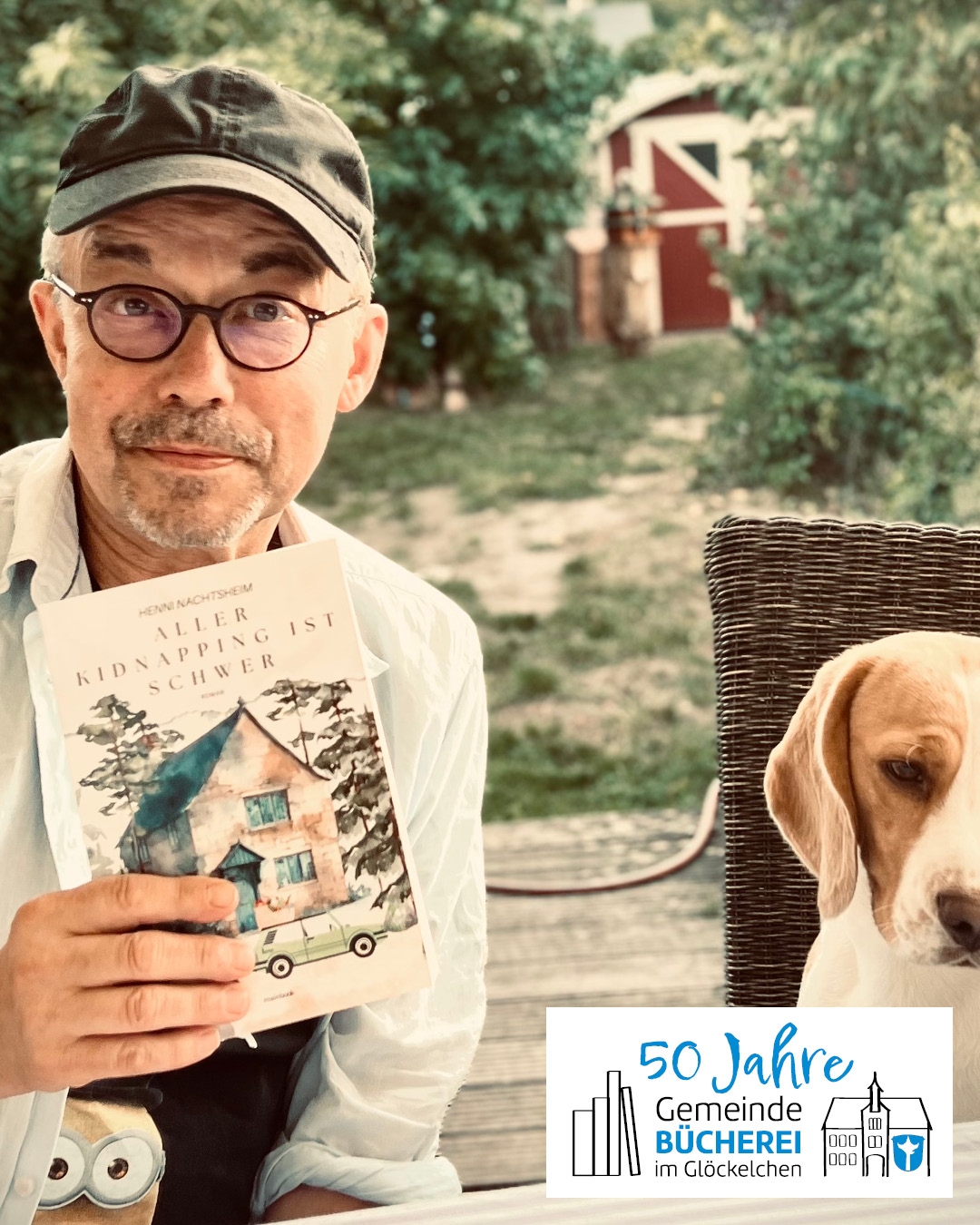 Lesung von Henni Nachtsheim Auf dem Foto ist Henni Nachtsheim zu sehen, er hält sein Buch in der Hand, neben ihm sitzt ein Hund