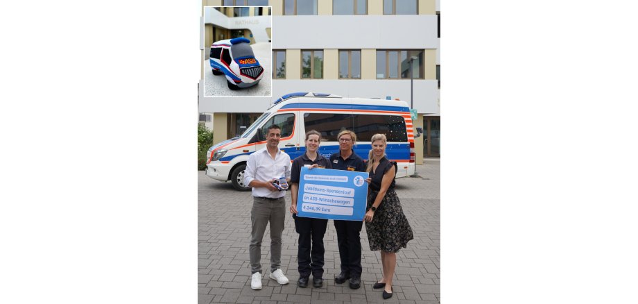 Bürgermeister Mark Pullmann und Organisatorin Sabrina Felger bei der Spendenübergabe an zwei ehrenamtliche Helferinnen des ASB-Wünschewagens vor dem Rathaus - der ASB-Wünschewagen befindet sich im Hintergrund und die Plüschausgabe sieht man im kleinen Bild