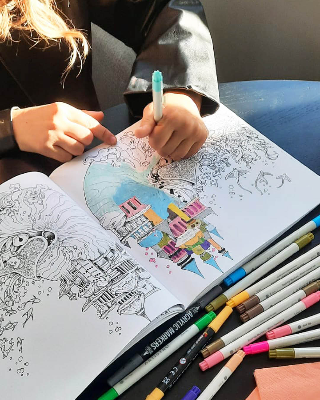 Café kreativ – freitags im ZIMMnER Auf dem Bild sieht man ein Malbuch und Farbstifte