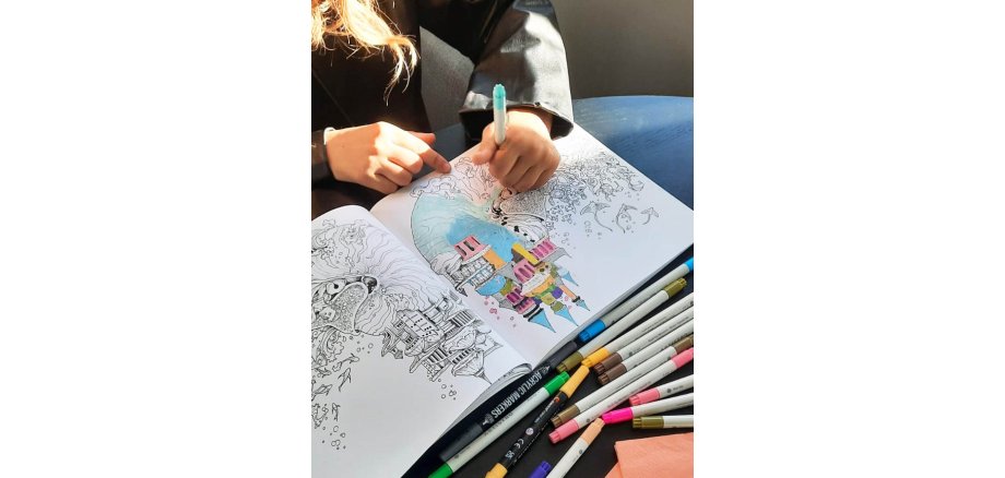 Auf dem Bild sieht man ein Malbuch und Farbstifte