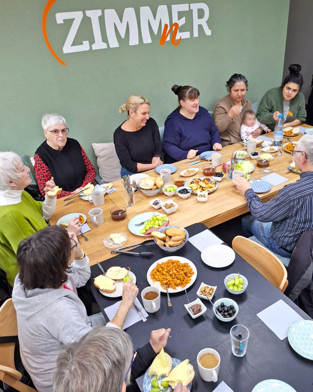 Im Foto sind Teilnehmende am Frühstückstisch zu sehen